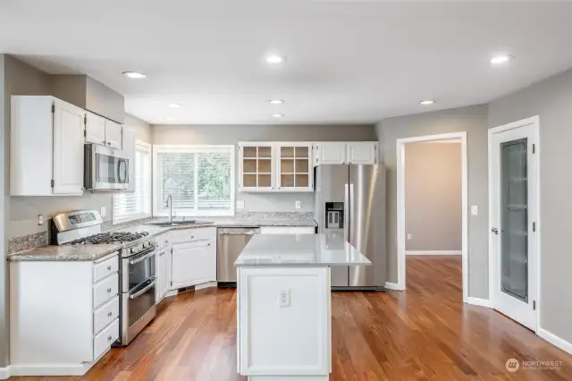 Spacious kitchen with quartz countertop island, gas range w/double ovens, newer refer and beautiful dense Peruvian Olive hardwood floors throughout house.