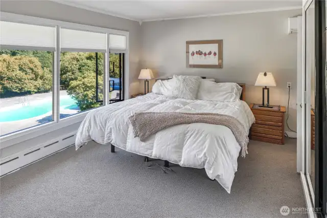 The primary bedroom, on the main level, is just down the hall from the living room. The sun will welcome you each morning as these floor to ceiling windows face east.
