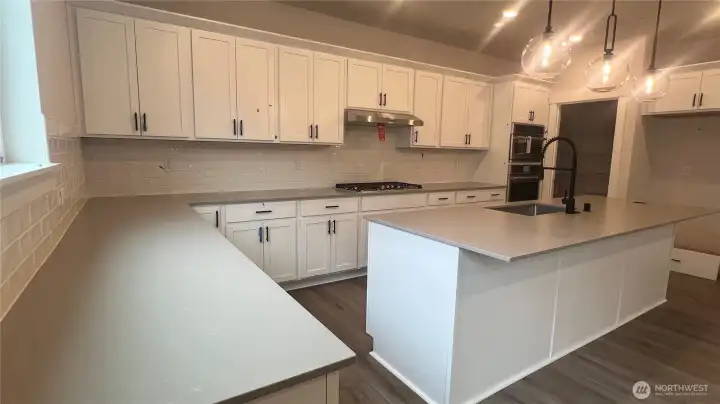 Quartz counters, full height backsplash, under cabinet lighting, hanging pendant lights & gas stove