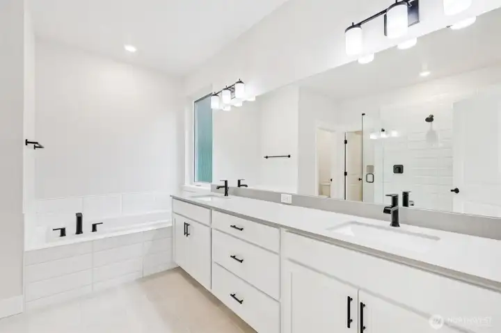 Large quartz counter slab, undermount dual sinks, deep drawers and plentiful storage.  Gorgeous 12x24 tile flooring and upgraded black hardware throughout.