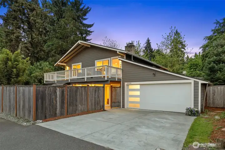 Exterior of the home showing expansive deck, attached garage, and large fenced lot with room to play and entertain.
