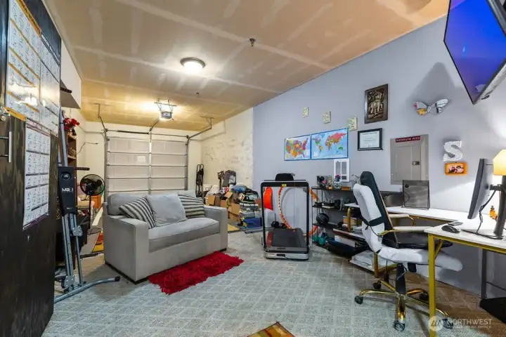 This incredibly oversized garage functions as a versatile flex space, offering ample room for a home gym, private office, and comfortable lounge area while still providing dedicated space for vehicle parking.