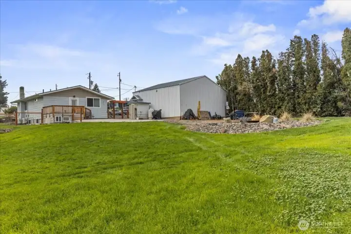 Back view of yard showing shop, firepit, trees, property ling.