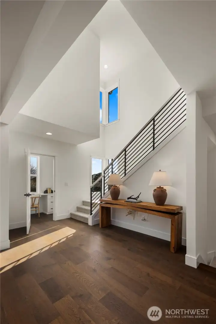 Main Level Landing: Open landing with soaring ceilings and sleek modern railing creates a bright, airy transition between levels. Large windows flood the space with natural light, offering a welcoming pause point that enhances the home’s spacious flow.    Photos are from THIS model home at Foxmoore but are for visualization purposes only.