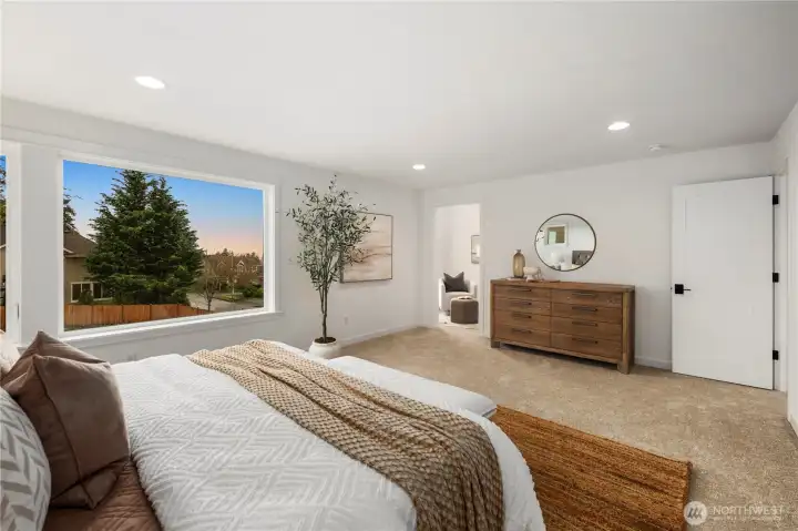 Primary Bedroom Alternate View: Large picture window frames territorial scenery, enhancing the room’s open feel. Direct access to the sitting room and ensuite bath makes this a true owner’s sanctuary.    Photos are from THIS model home at Foxmoore but are for visualization purposes only.