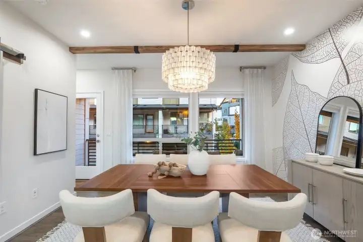 Large dining space with custom wallpaper, wood beams, and feature chandelier.