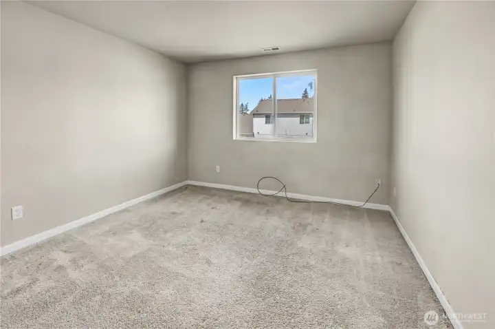 Bedroom on upper level with carpet flooring at back of house.