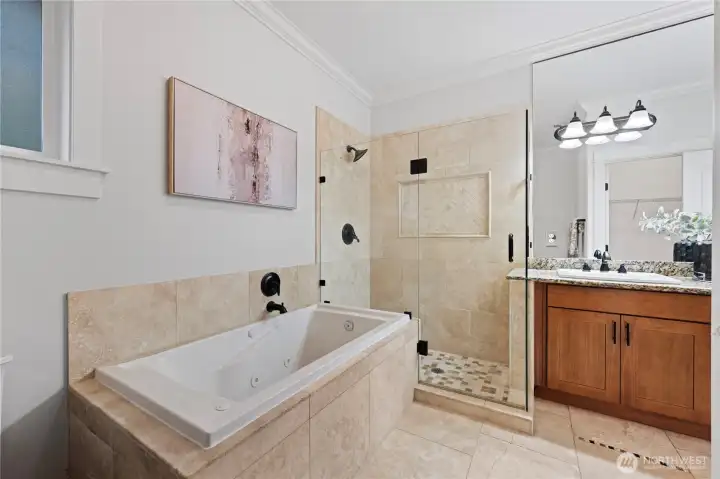 View of the primary suite bath with heated floors, separate tub and walk-in shower.