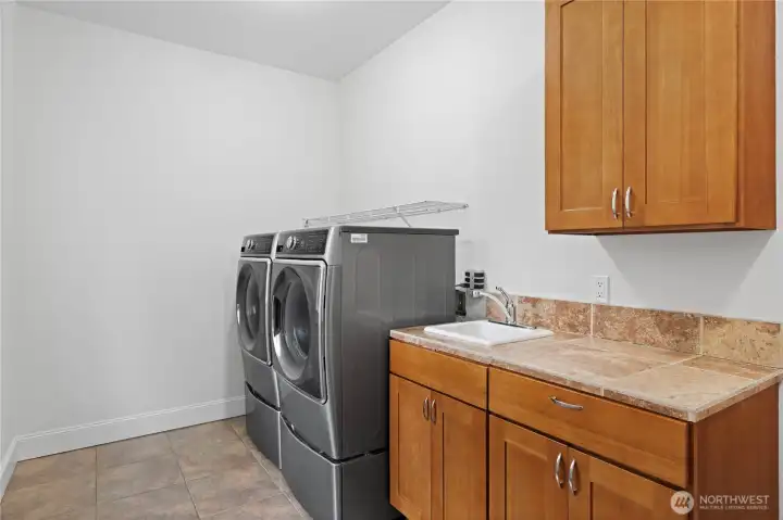 Large laundry room with cabinets and sink and washer & dryer stay. This room also has a door to the back yard and door to the garage.