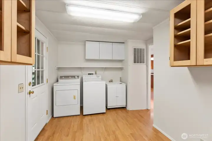 Another view of the multipurpose laundry room complete with utility tub and storage cabinets.