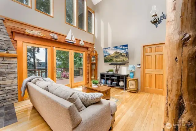 Living room with water view, vaulted ceiling and beautiful log pillars. Walks out onto wrap-around trex deck.