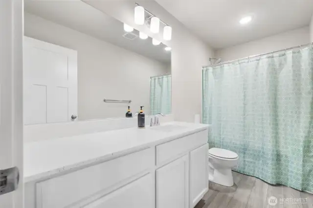 The upstairs full bath features modern finishes, a spacious vanity, and a tub/shower combo — perfect for guests, kids, or anyone needing a little extra space.