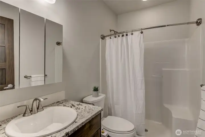 Lower-level ¾ bathroom with step-in shower and cool tile floor.