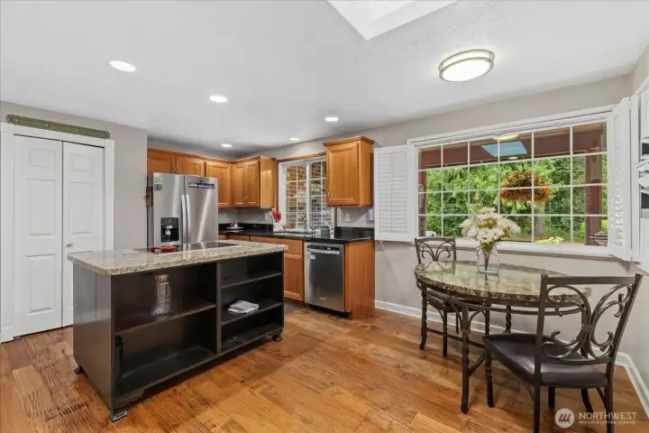 Spacious kitchen with granite island, stainless steel appliances, and breakfast nook overlooking the peaceful front yard.