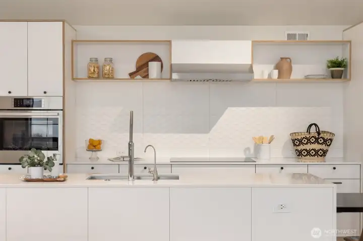 The chic modern kitchen features beautiful backsplash tile and an impressive 14-plus-foot quartz-topped island with waterfall edge