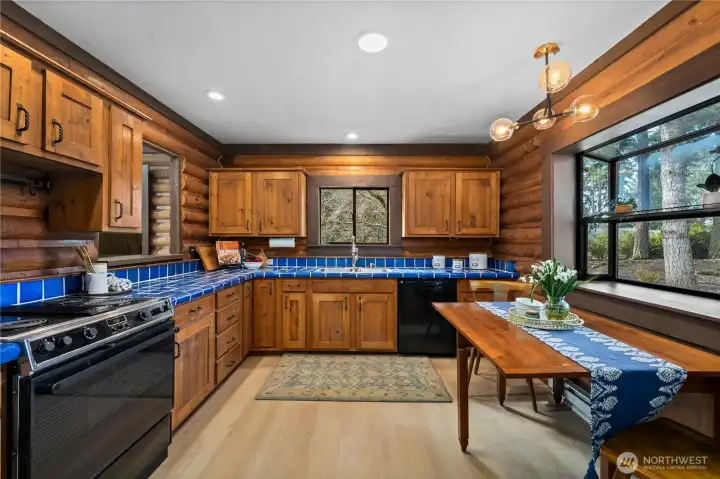 Kitchen includes ample cabinet space + charming blue tiled countertops.