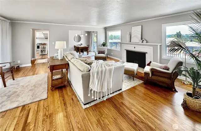 Spacious living room with rich oak floors, log burning fireplace, crown molding, full west wall of windows that offer so much natural light and east facing windows for morning sun and territorial views!