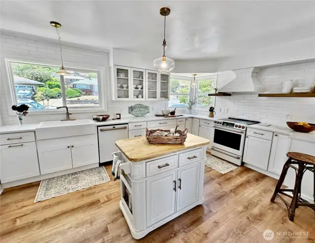 Updated kitchen with new cabinets, floating shelves, farm sink, Cafe range/oven and dishwasher, glass pendant light fixtures and new luxury vinyl plank flooring.