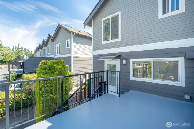 Generous west-facing ack deck off kitchen covers carport.