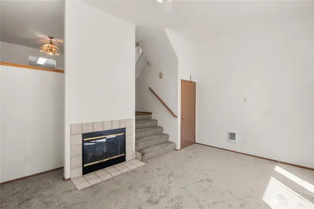 Woodburning fireplace in living room. Stairs lead to dining room and kitchen.