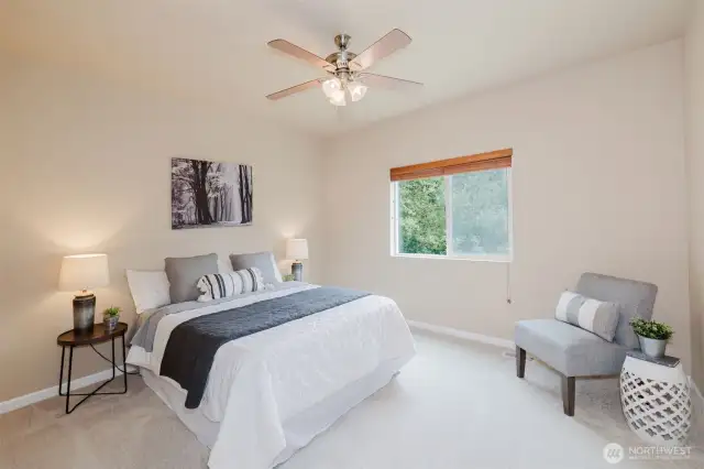 Spacious primary bedroom with large window and ceiling fan