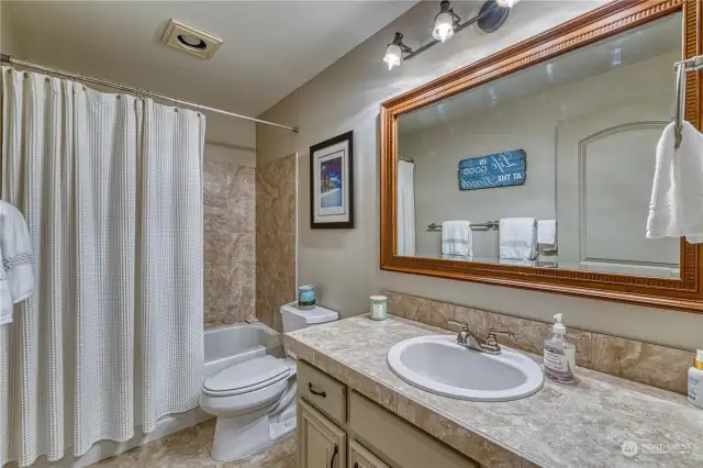 Full guest bathroom is nicely updated with tile floors, tile counter top and tile shower surround.