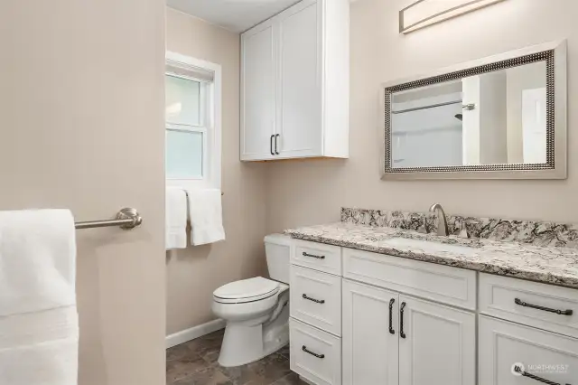 Guest bath was recently remodeled and has newer flooring, toilet, vanity, cabinets, mirrors, lighting, sink and faucet. A full-length mirror (unseen here) hides a secret closet which houses the hot water heater and extra storage.