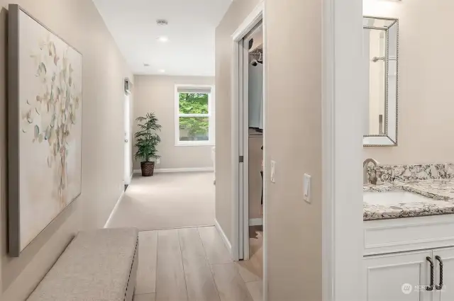 A private and separate hall leads into the Primary Bedroom suite. The Primary Bathroom can be seen on the far right, the walk-in-closet is in the middle, and the BR is at the far end.