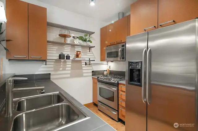 The kitchen features stainless steel appliances, a sleek gas stove, and ample storage.