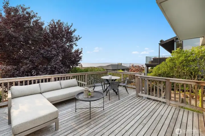 The expansive cedar deck extends the living space outdoors, offering room for both lounging and dining. Surrounded by mature landscaping, it provides privacy while opening to views of Shilshole Bay.
