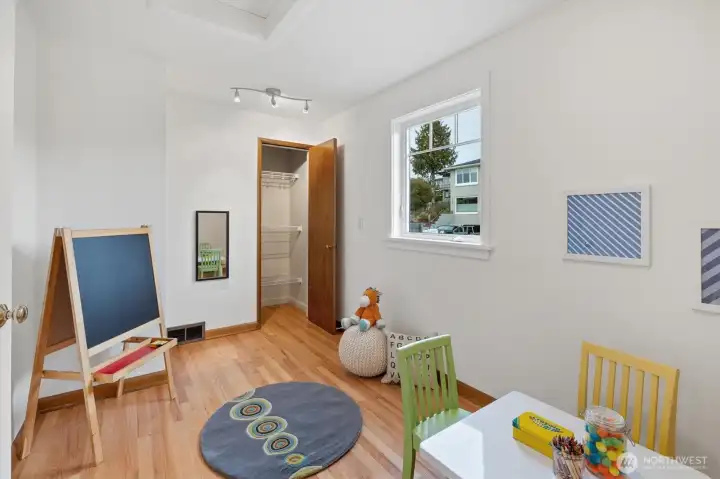 The third main floor bedroom, currently staged as a playroom, features hardwood floors, a large closet, and ample natural light—offering flexibility for a variety of needs.