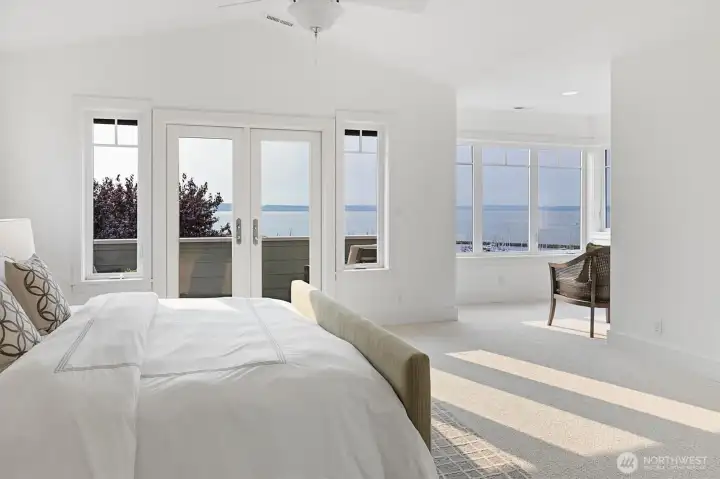 The primary suite is the retreat we all dream about—vaulted ceilings, walls of windows, and French doors opening to a private balcony with water views. A sunlit sitting area adds space to relax, making this room a true sanctuary.