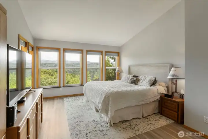 Large primary bedroom with several windows,  The view from the windows is a totally unobstructed view of Mt. Rainier.  Just imagine waking up in the morning to see Mt. Rainier in all of its glory and various moods.