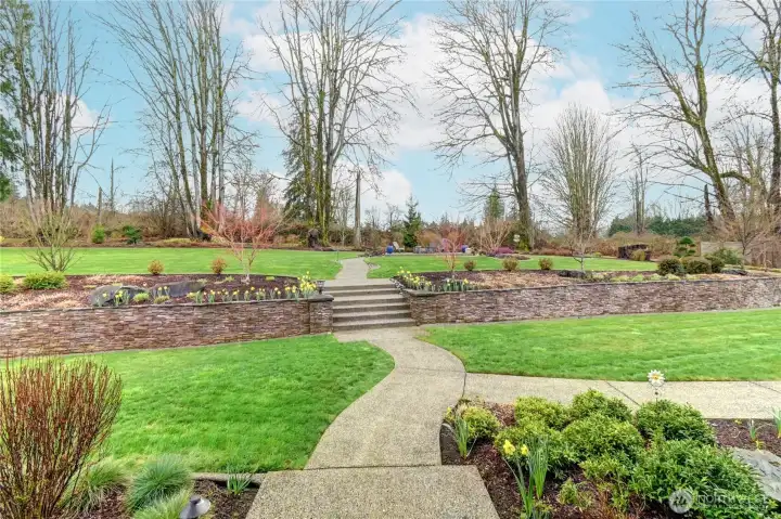 Expansive backyard retreat featuring a custom firepit patio, winding walkways, and beautifully curated landscaping.