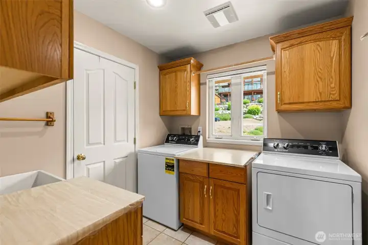 This laundry room has lots of storage and a laundry sink. The washer and dryer are included in the sale.