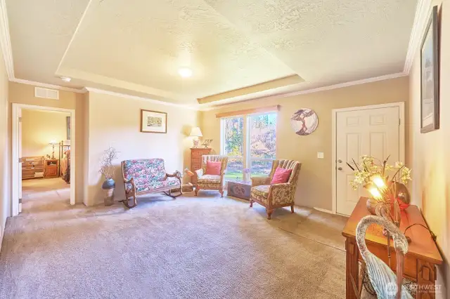 Front door opens to living room with charming tray ceiling