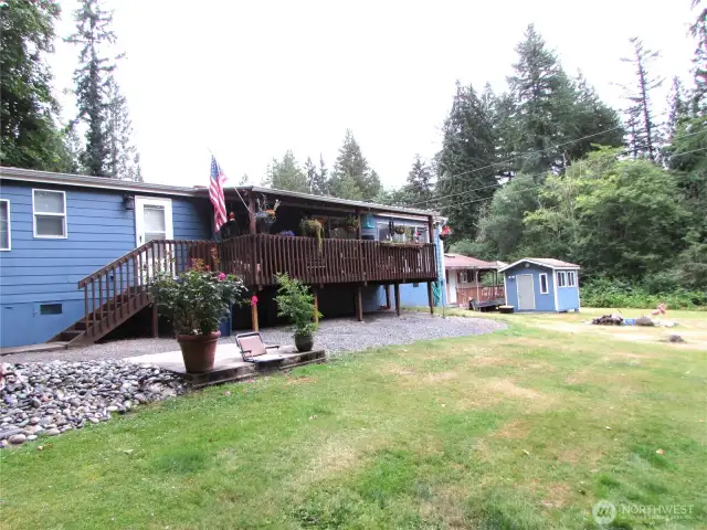 Big covered deck is ideal in all-weather settings. Out buildings to rear in photo have power, abundant storage w/ added habitable room for future Studio or Bunk house.