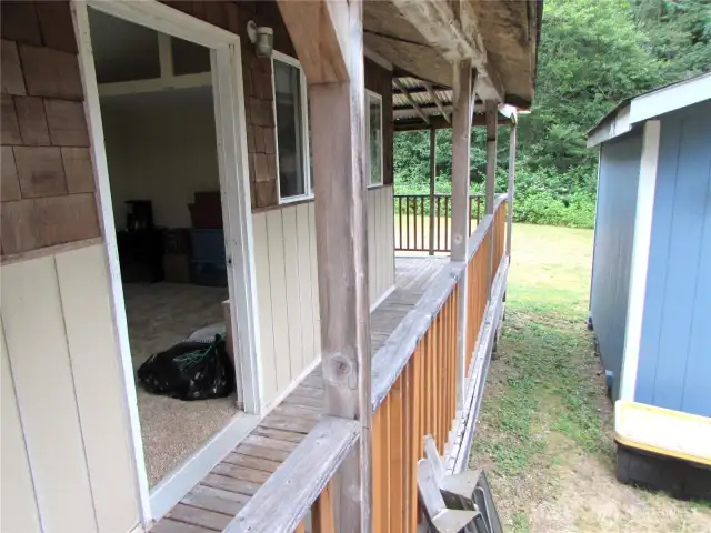 Covered walkway continues to large deck area in back overlooking where a RV can be stored.