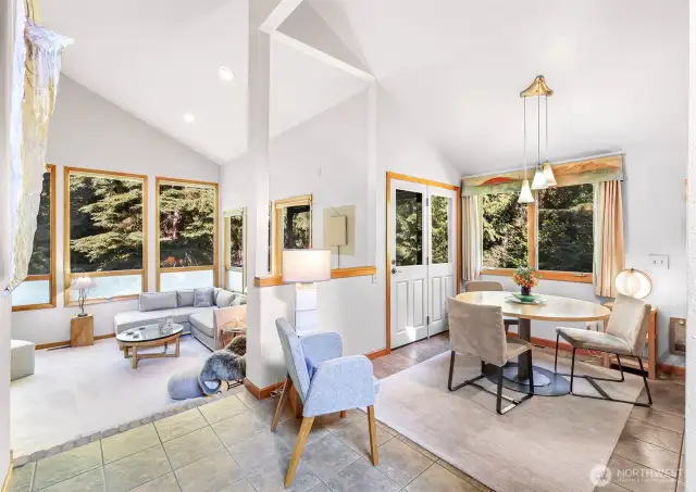 Sunlight pours into this open-concept living and dining space through oversized windows, highlighting soaring ceilings and tranquil views.