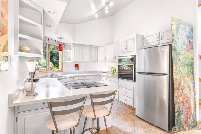 Clean cabinetry, sleek stainless appliances, and modern lighting create a welcoming space that opens to treetop views.