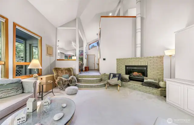 The sunken living room invites you in with soft carpet, tranquil colors, and cozy seating surrounded by nature.