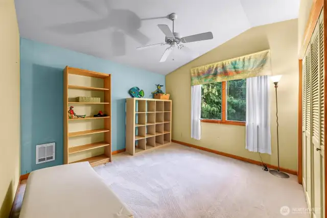 Spacious third bedroom with vaulted ceilings, a large closet with louvered doors, and soft natural light