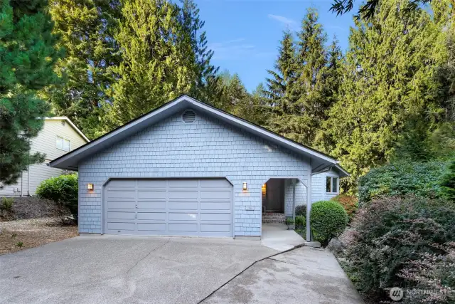 Framed by mature landscaping and lush evergreens, this inviting entry blends privacy and natural beauty with welcoming symmetry.