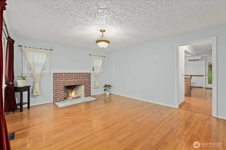 Warm hardwood floors and a brick fireplace create a warm focal point.