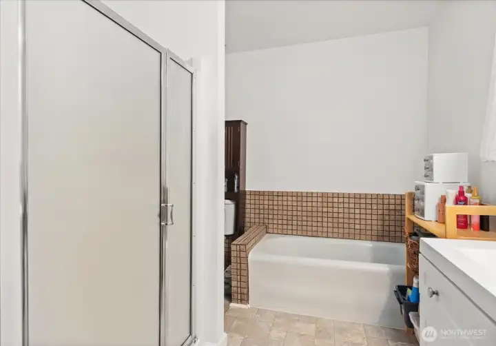 A clean white vanity, large mirror, and natural light from the window create a bright, functional space.