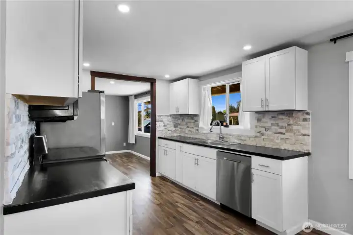 Updated kitchen with stone backsplash and stainless steel appliances