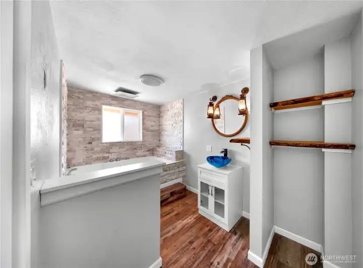 Primary bath with live edge open shelving for storage and large jetted soaking tub! Look at all this natural light!
