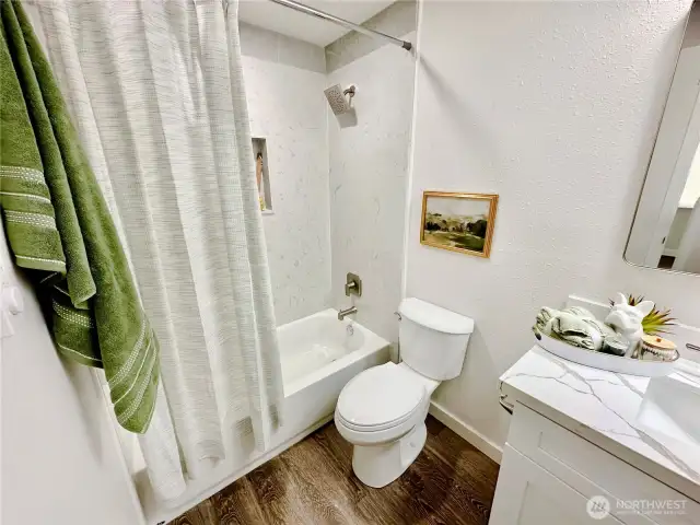 View of tub shower, more quartz on counters and shower surround.