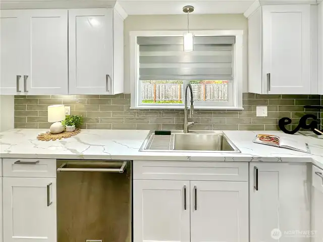 Beautiful quartz countertops and stainless sink with window overlooking rear yard.