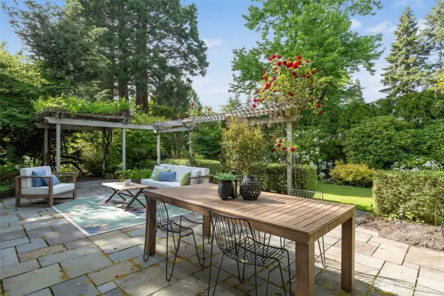 The practical and elegant backyard features a large level patio, mature plantings and charming garden features.